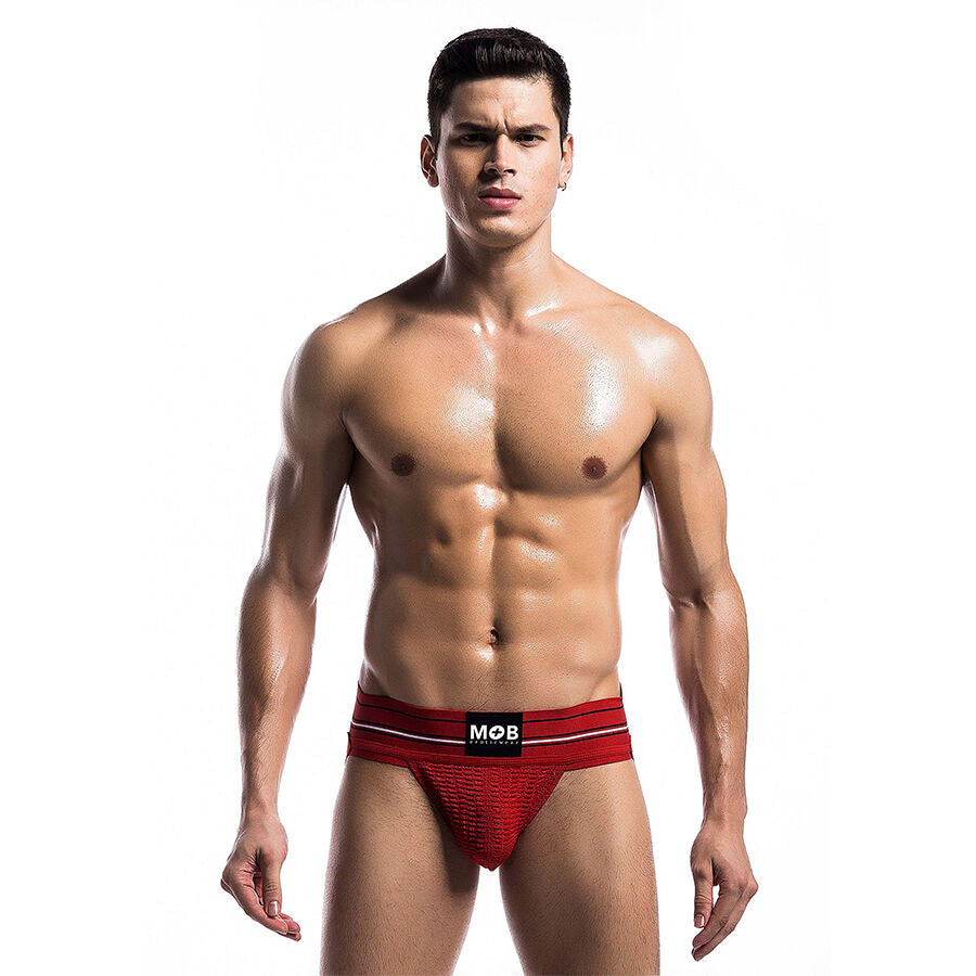 String homme rouge sur modele torse nu, vue frontale : pochette structuree a l'avant, coupe minimaliste extensible qui souligne la silhouette masculine avec audace.
