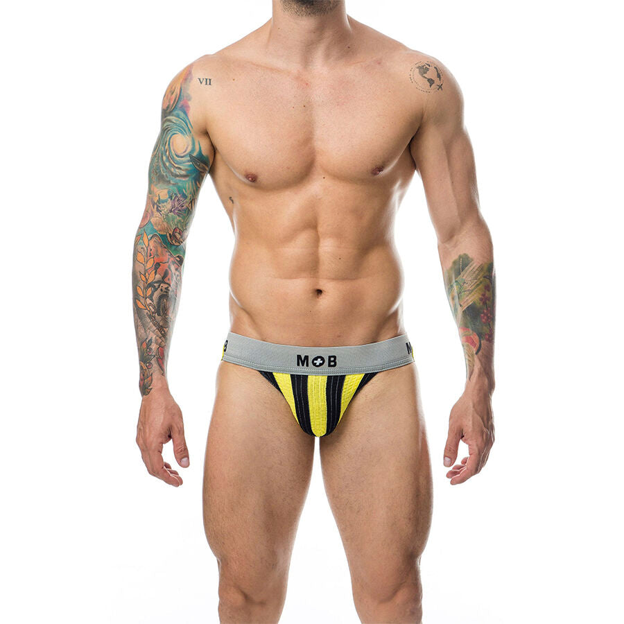 Jockstrap homme raye jaune et noir MOB porte de face, large ceinture logotee et pochette galbante, presente sur un torse masculin tatoue et muscle.