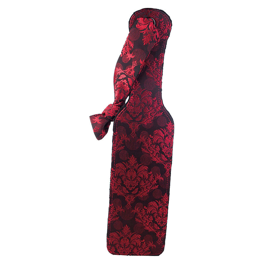 Paddle double face Scandal en brocart rouge et noir motif floral, palette souple a noeud decoratif, presente debout sur fond blanc pour la fessee douce ou ferme.