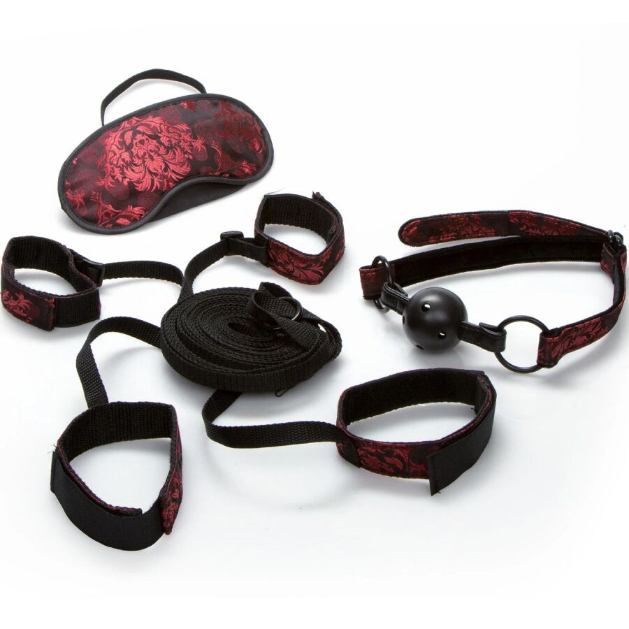 Kit de contention de lit Scandal avec sangles brocart rouge, bandeau, baillon boule et manchettes a mousquetons, presente etale sur fond blanc, ensemble complet.