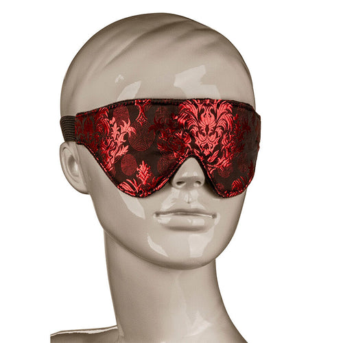 Masque occultant Scandal brocart rouge et noir porte sur un mannequin gris neutre, illustrant le maintien et la couverture des yeux pour la privation sensorielle.