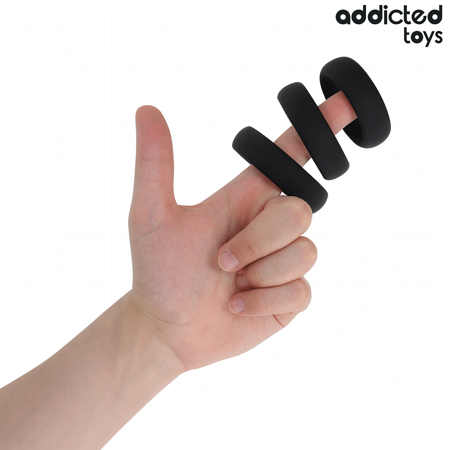 Trois anneaux peniens plats en silicone noir Addicted glisses sur des doigts pour montrer leur souplesse et leurs diametres, cockrings de maintien de l'erection.