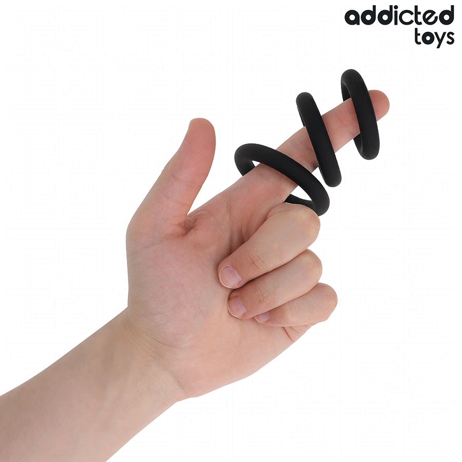 Trois anneaux peniens en silicone noir Addicted enfiles sur des doigts pour montrer souplesse et diametres, set de cockrings de maintien de l'erection.