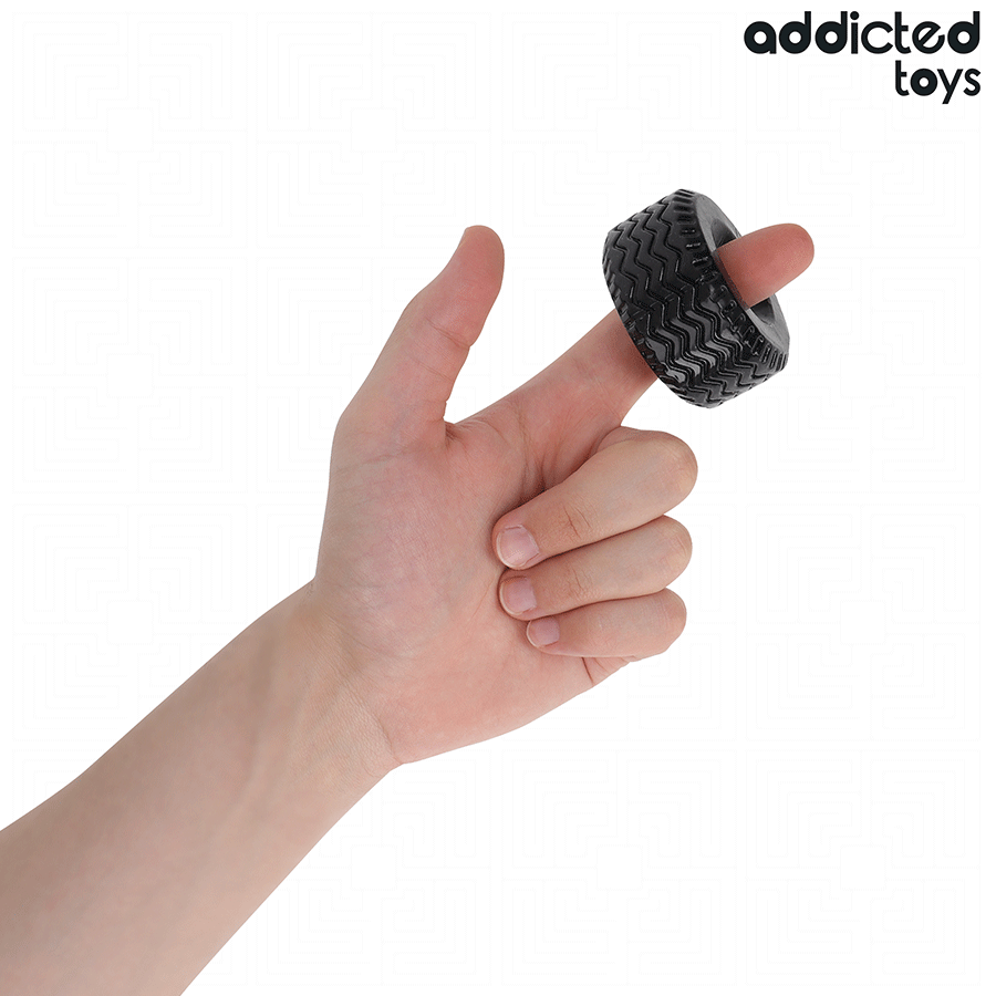 Anneau penien extra epais en silicone noir texture Addicted tenu au creux de la main pour illustrer sa taille compacte, cockring de maintien de l'erection.