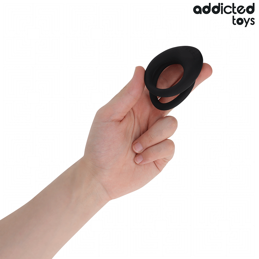 Anneau penien double texture en silicone noir Addicted tenu entre les doigts pour montrer ses boucles et son relief, cockring de maintien de l'erection.