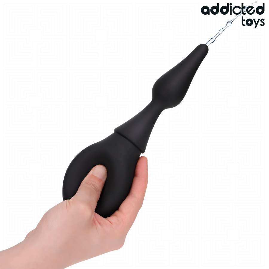Poire de douche intime Addicted tenue en main, canule effilee en silicone souple projetant un jet d'eau, demonstration de l'usage nomade et discret.