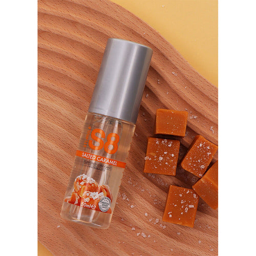 Flacon S8 lubrifiant gourmand caramel sale base eau pose a plat sur bois, vu de profil avec cubes de caramel, format 125 ml comestible et effet chauffant leger