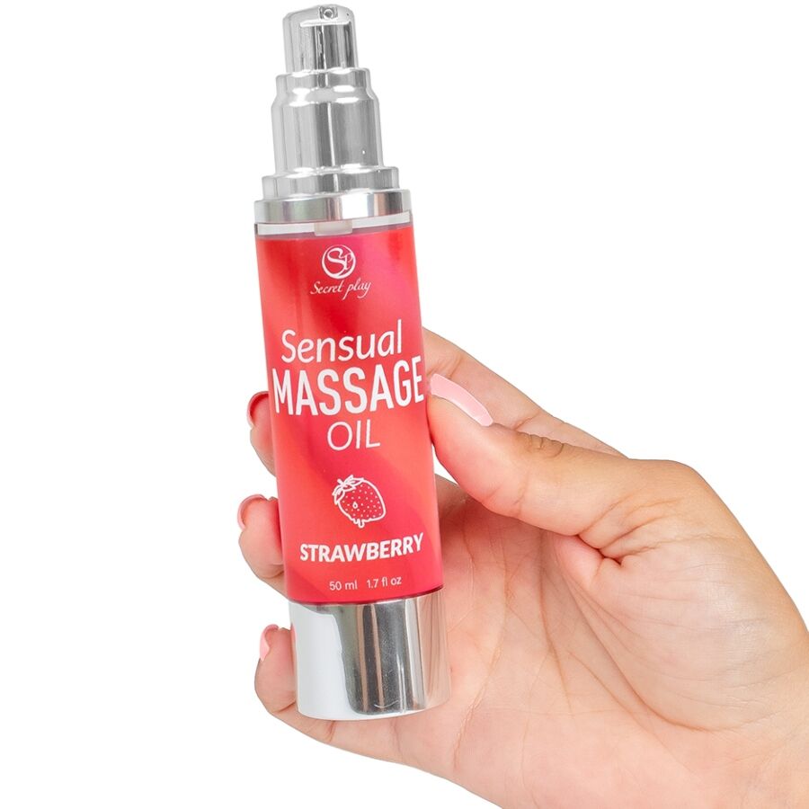 Flacon Sensual Massage Oil strawberry tenu en main, pompe airless argentee, etiquette rouge, format 50 ml pour doser facilement l huile de massage parfumee.