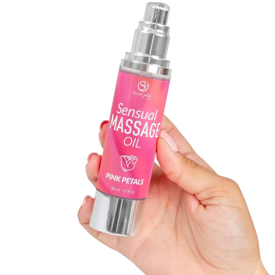 Flacon Sensual Massage Oil Pink Petals tenu en main, pompe airless argentee, design rose, format 50 ml pour appliquer l huile de massage parfumee aux petales.
