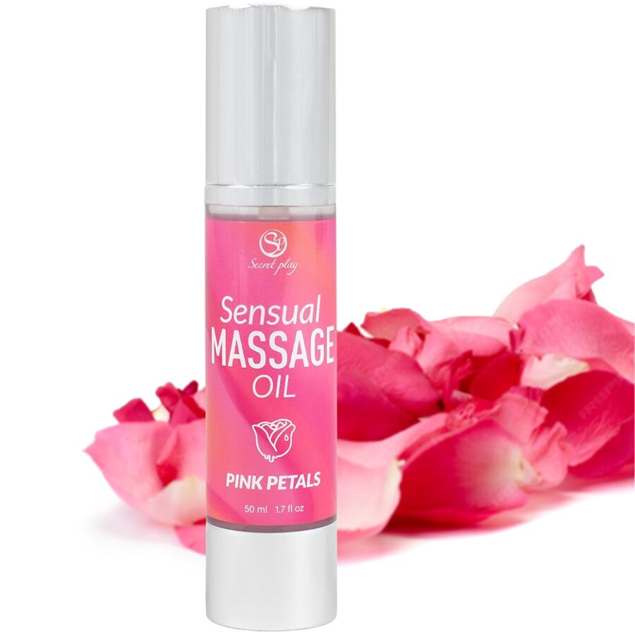 Flacon Sensual Massage Oil Pink Petals pose pres de petales de rose, etiquette rose Secret Play, mise en scene florale de l huile de massage sensorielle 50 ml.