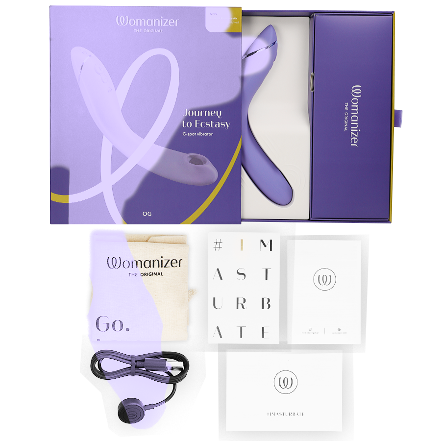 Boîte violette du Womanizer OG, câble de charge et cartes de notice à côté, stimulateur G-spot lavande par ondes d'air, rechargeable. Présentation complète du coffret cadeau.