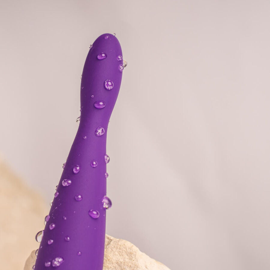 Gros plan de la tige du plug anal Teazer violet couverte de gouttes d'eau, silicone souple incurvé, illustrant l'étanchéité de ce stimulateur point P flexible.