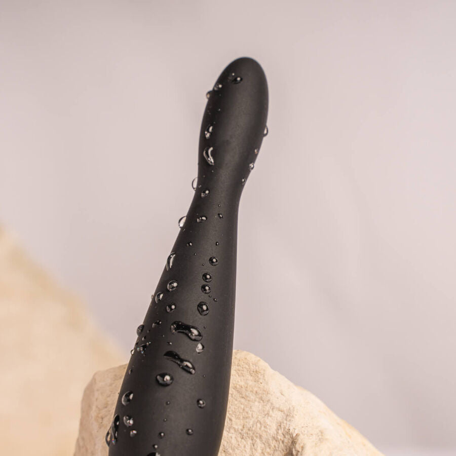 Gros plan du plug anal Teazer noir couvert de gouttes d'eau, tige fine incurvée en silicone, mettant en avant l'étanchéité de ce stimulateur point P flexible.