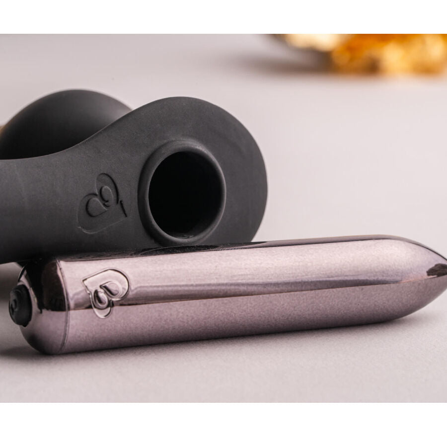 Gros plan de la bullet argentée logée dans le combiné plug-anneau noir, jonction et logo gravé visibles, surfaces lisses posées sur fond clair épuré et neutre.