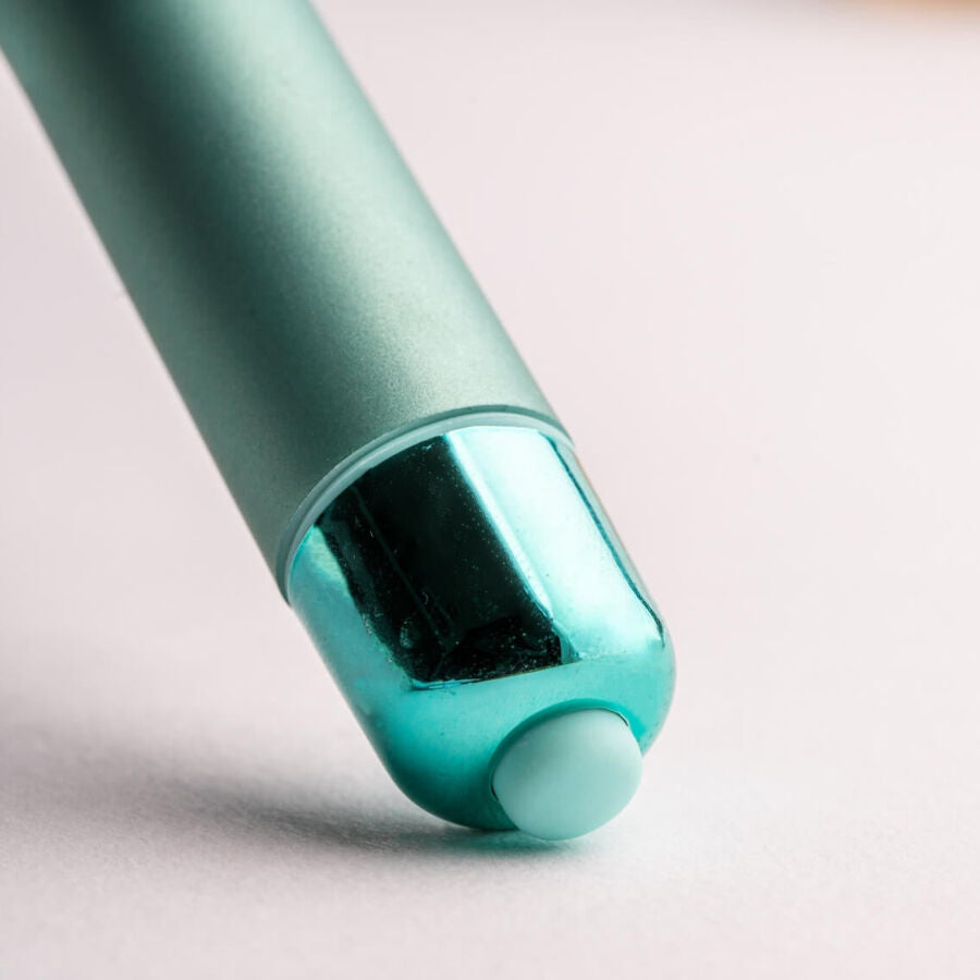 Macro de la base du bullet vert montrant le capuchon de commande clair et la jonction métallisée, corps lisse posé sur surface neutre, sans contexte corporel.