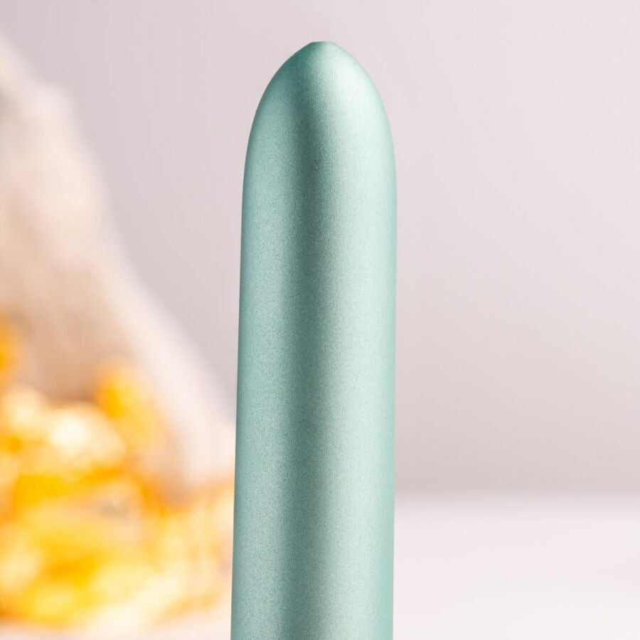 Gros plan de la pointe arrondie du bullet vert d'eau, surface satinée lisse et éclat doré flouté en fond, mettant en avant la finesse du mini vibromasseur.