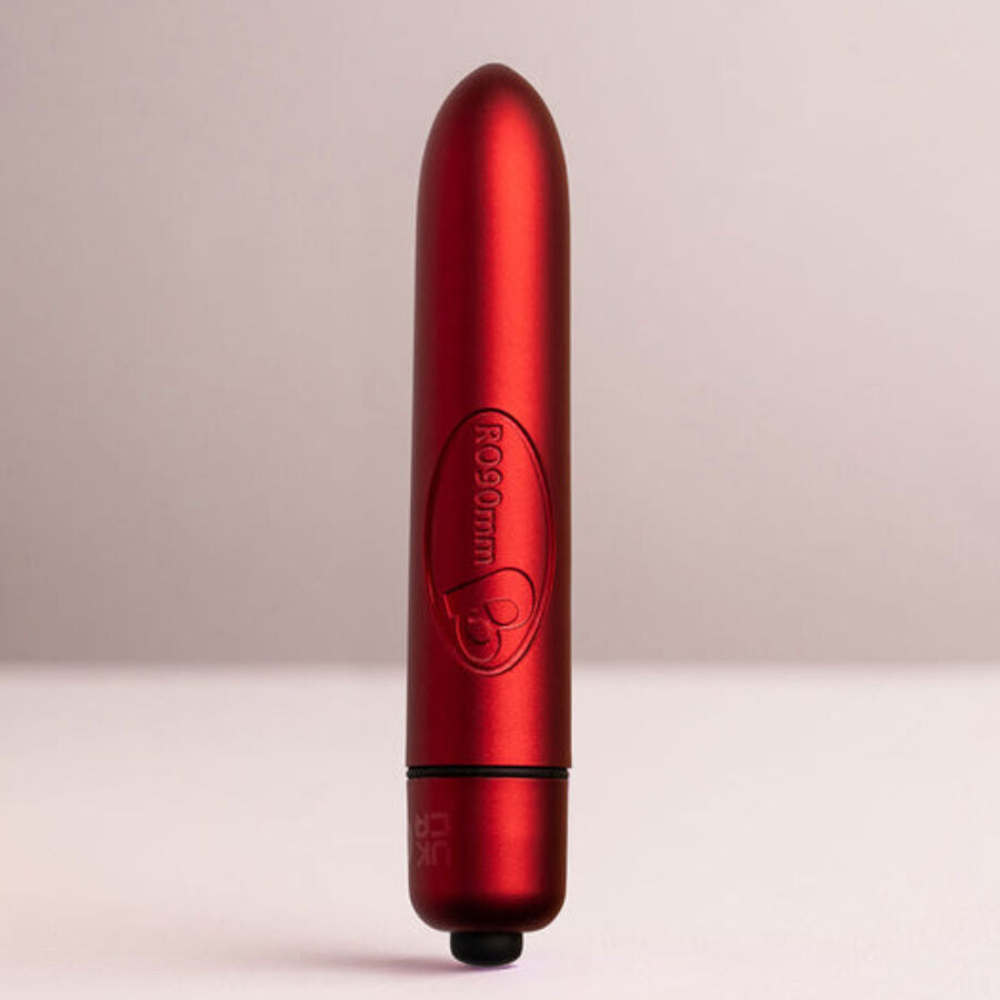 Bullet rouge dressé debout sur fond clair, logo Rocks-Off gravé et embout de commande à la base, corps cylindrique satiné lisse sans relief anatomique.