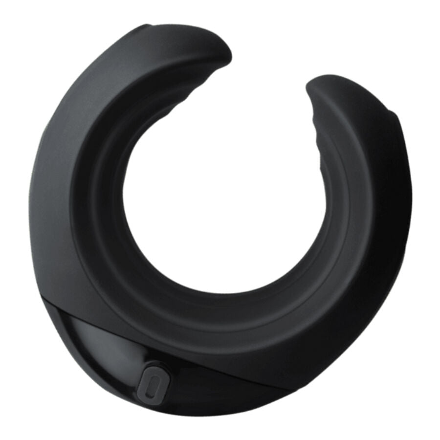 Anneau pénien vibrant noir en silicone à la forme en croissant ouvert, posé seul sur surface beige, base à balle vibrante intégrée, finition lisse mate.