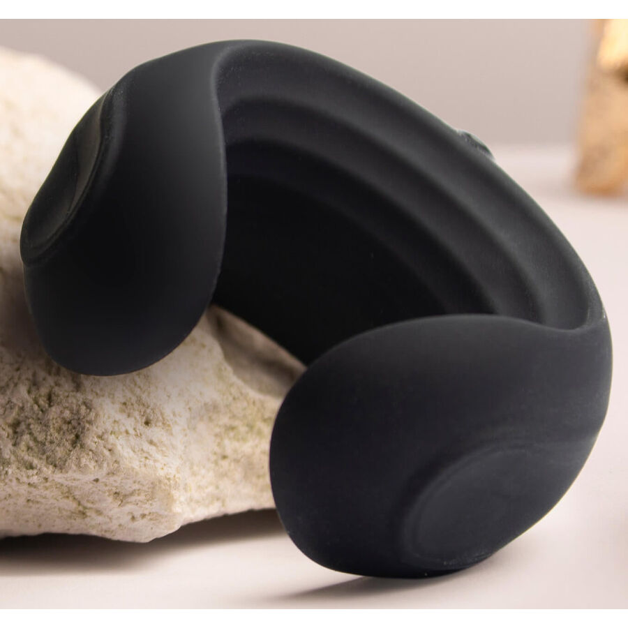 Cockring vibrant noir appuyé sur une pierre claire, forme galbée en croissant et base bombée bien visibles, finition silicone mate sans aucun détail anatomique réaliste.