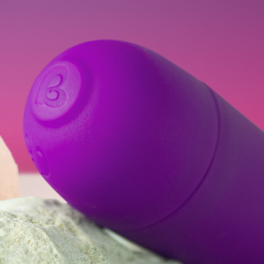 Gros plan de la base du mini wand violet montrant le bouton de commande gravé du logo Rocks-Off et le manche élancé, silicone lisse non anatomique du mini wand.