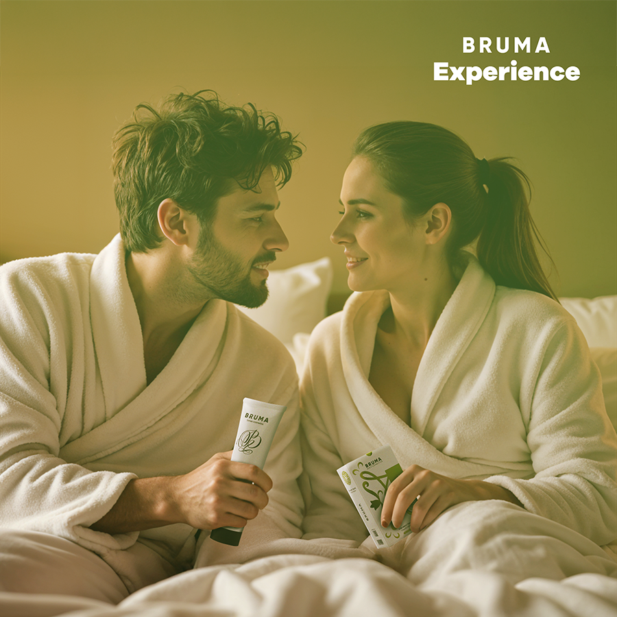 Couple souriant en peignoir tenant un tube Bruma sur fond vert, scene tendre illustrant le coffret sensoriel pasteque a gel vibrant utilise a deux