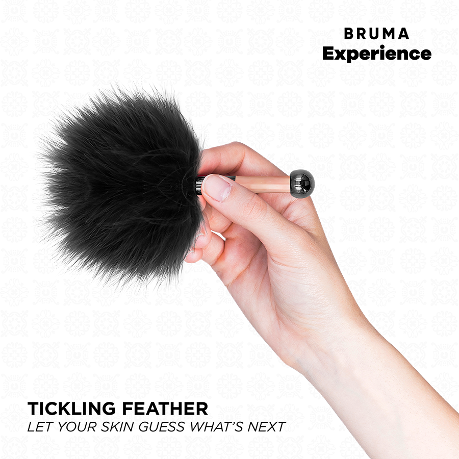 Plume a chatouiller noire Bruma tenue en main, gros plan sur le pompon duveteux, accessoire sensoriel du kit pina colada pour titiller la peau en douceur