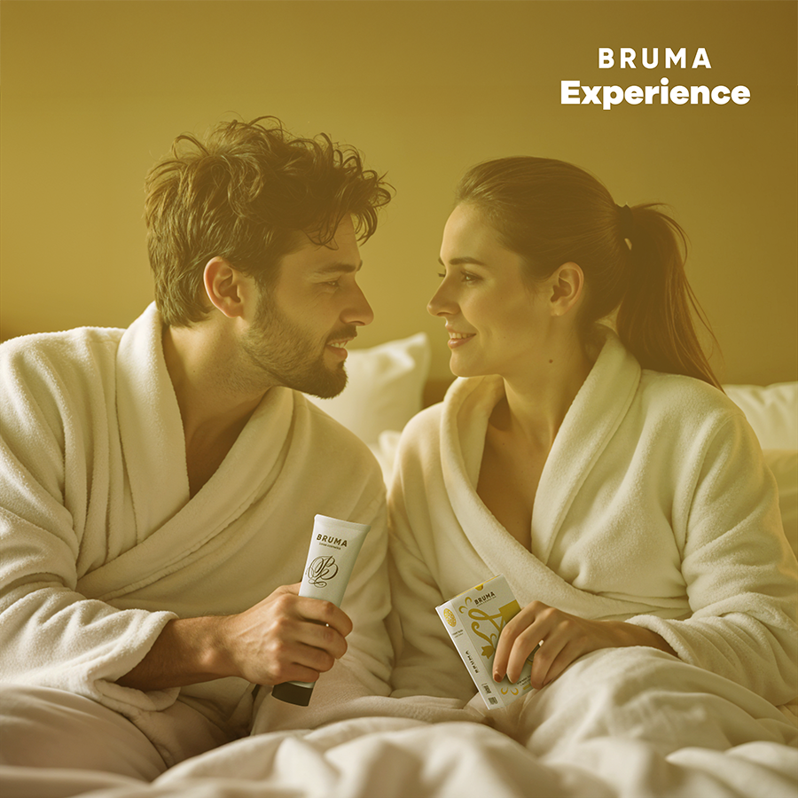 Couple souriant en peignoir allonge tenant un tube Bruma sur fond dore, scene tendre illustrant le kit tropical pina colada a gel vibrant a partager a deux