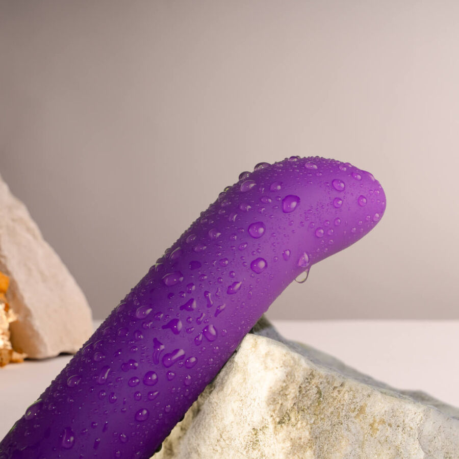 Gros plan de la tige du vibromasseur point G violet couverte de gouttes d'eau, silicone profilé illustrant l'étanchéité du stimulateur Chaiamo G rechargeable.