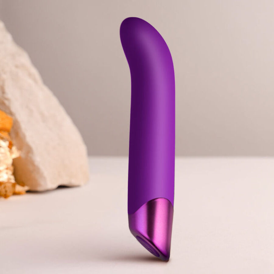 Vibromasseur point G violet dressé devant des pierres claires, tige courbée en silicone et base métallisée, stimulateur Chaiamo G 10 modes étanche rechargeable.