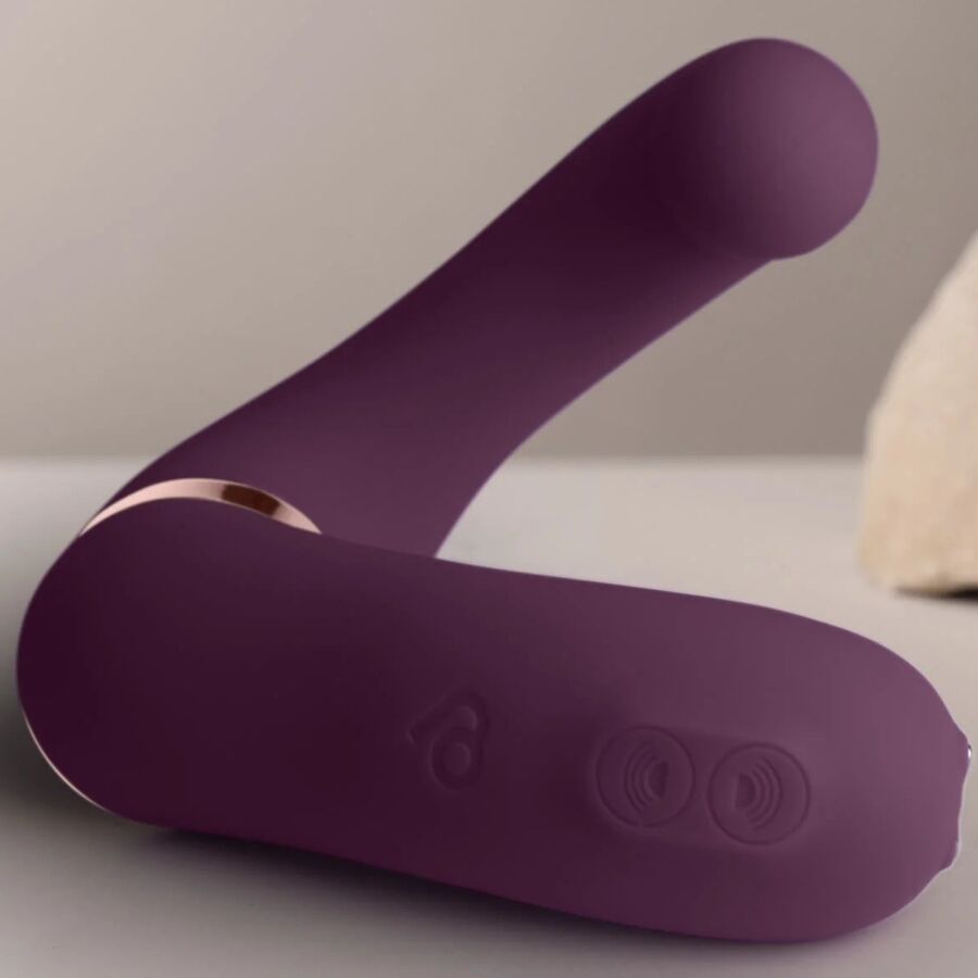 Double vibromasseur violet en U posé à plat, boutons de commande visibles sur la base et liseré doré, deux bras souples en silicone mat non anatomique.