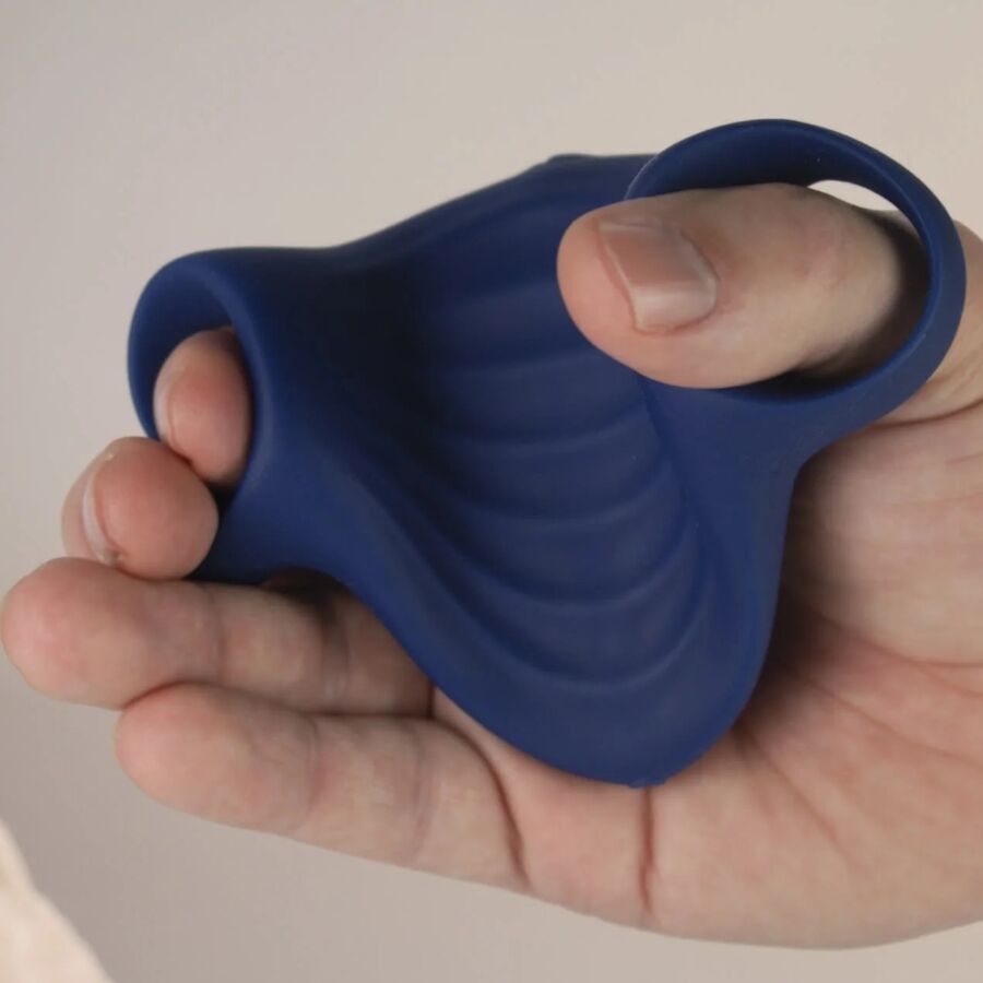 Masturbateur Palm bleu marine tenu dans une main avec les doigts glissés dans les passants, illustrant la prise de cette gaine vibrante flexible en silicone.