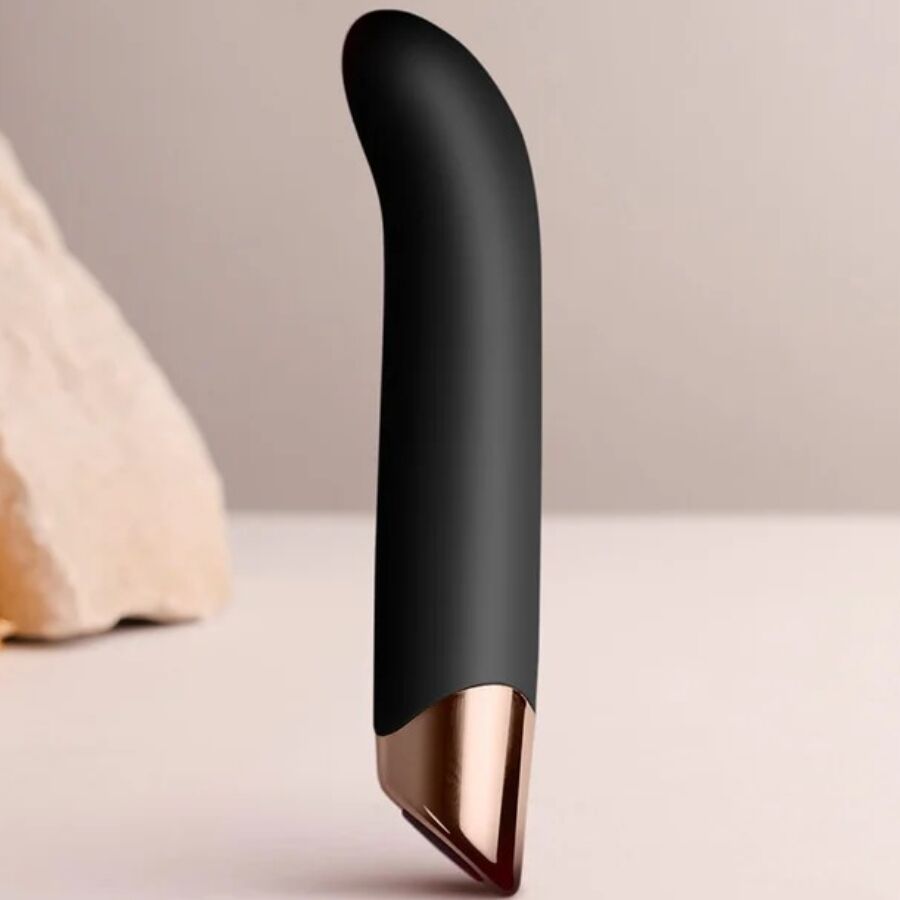 Vibromasseur point G noir dressé devant une pierre claire, tige courbée en silicone et base dorée brillante, stimulateur Chaiamo G 10 modes étanche rechargeable.