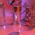 Parfum aux phéromones femme aux notes d'agrumes, flacon roll-on dore sur fond rose et fleurs, eau de parfum bergamote rose jasmin musc blanc longue tenue Eye Of Love.