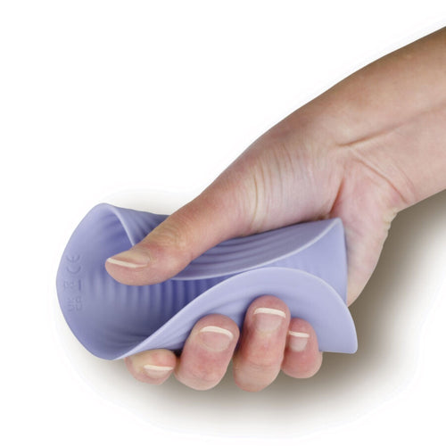 Masseur intime NIYA N5 en silicone souple plie dans une main, demonstration de la flexibilite de la coquille lilas pour une stimulation externe douce et rechargeable