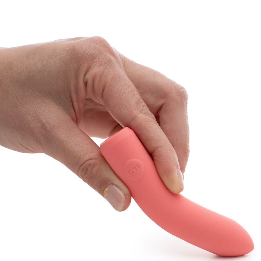 Bullet corail saisi à pleine main, cylindre lisse à bout arrondi enveloppé par les doigts repliés, vue rapprochée illustrant la prise du produit sur fond blanc parfaitement épuré.