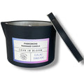 Bougie de massage gourmande Lilac Dream, pot noir Pheromone Massage Candle Love In Bloom couvercle entrouvert, cire karite fondante notes vanille bois de cachemire musc.