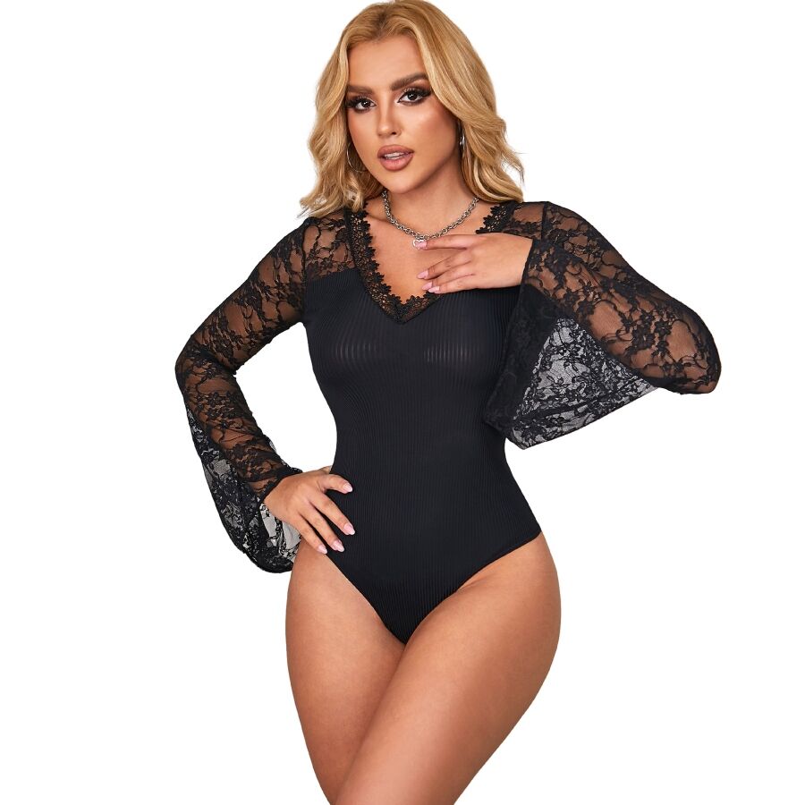 Teddy noir Subblime manches longues dentelle evasees, decollete en V et coupe echancree, porte de face par une modele, main a la poitrine, look elegant.