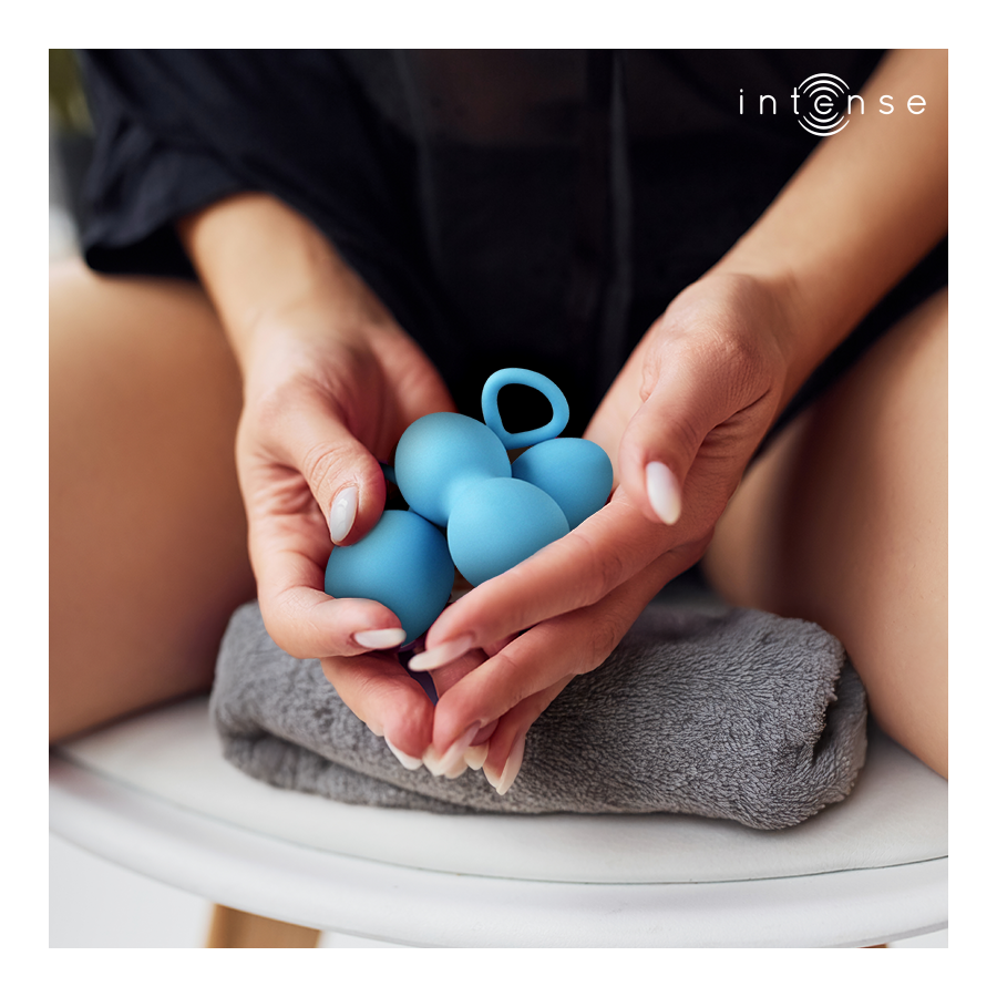 Boules de Kegel Charli bleues en silicone tenues au creux des mains au-dessus d'une serviette, double bille a anneau de retrait, entrainement du plancher pelvien