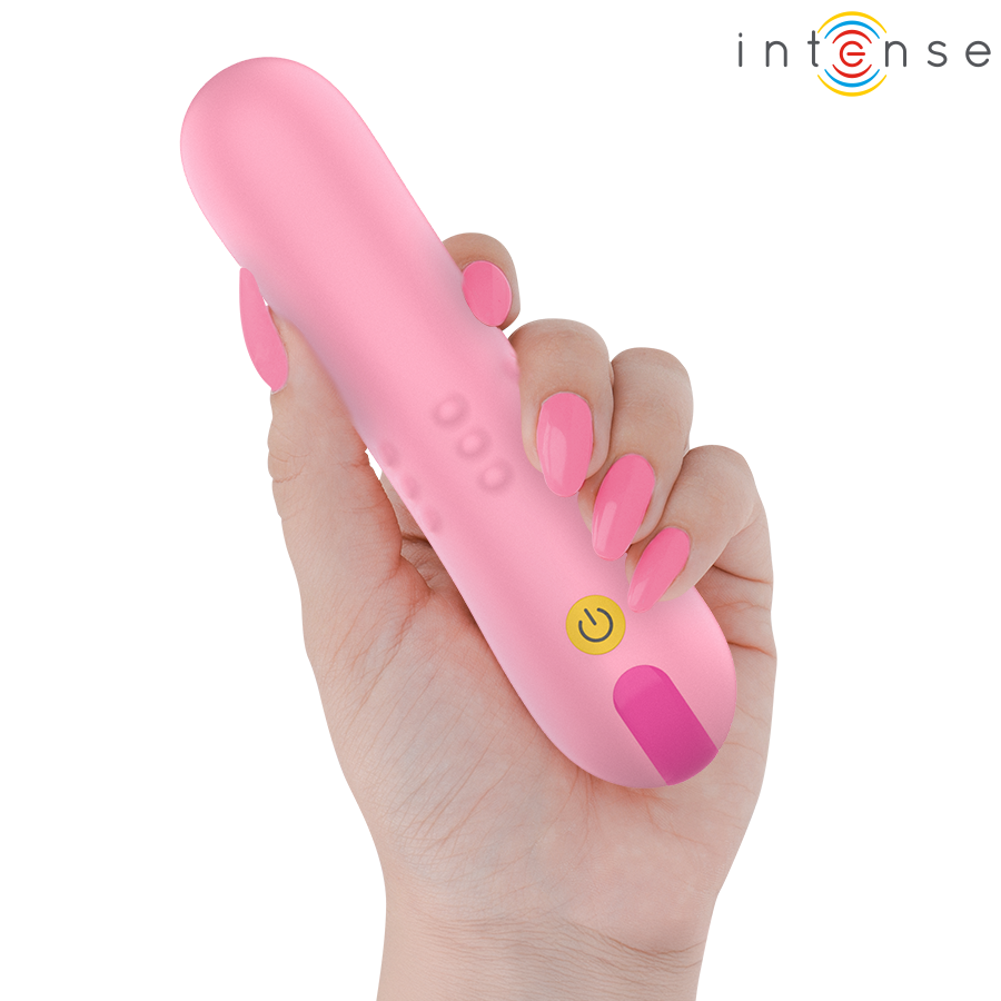 Mini vibromasseur Intense rose pastel a relief tenu dans une main aux ongles roses, bouton power, format compact ABS body-safe pour stimulation ciblee.