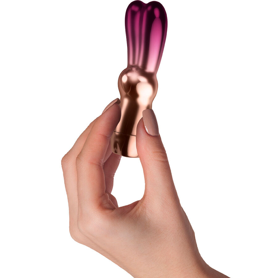 Mini vibromasseur lapin Bella tenu entre les doigts, gros plan revelant son format discret de poche et sa finition rose dore lisse, 10 vibrations.