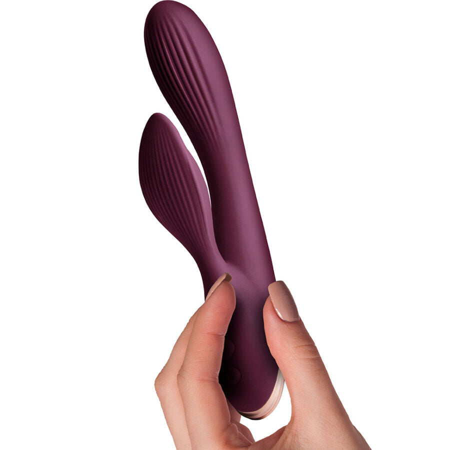 Vibromasseur rabbit Lyanna tenu en main, gros plan sur la flexibilite de la tige point G courbee et le stimulateur clitoridien prune, double moteur etanche.