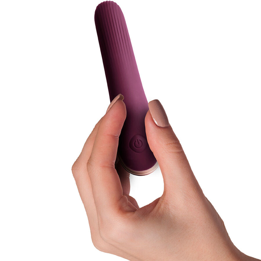 Vibromasseur discret Mia tenu en main, gros plan sur la courbe douce du corps prune et le bouton de commande, stimulation interne et clitoridienne etanche.