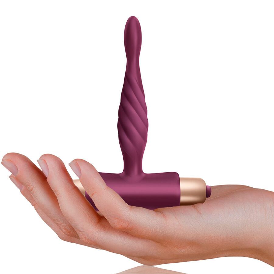 Plug anal vibrant Pharos pose sur une main, montrant l'embout en spirale, la base en T de securite et le bullet dore, format compact pour debuter etanche.