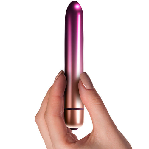 Mini vibromasseur fin Sepora tenu entre les doigts, gros plan sur la finition rose dore degrade et le format fin de sac a main, 10 niveaux d'intensite etanche.