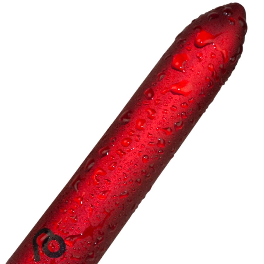 Gros plan du bullet vibrant rouge couvert de gouttes d'eau, finition métallisée perlée illustrant l'étanchéité de ce mini vibromasseur clitoridien rechargeable.