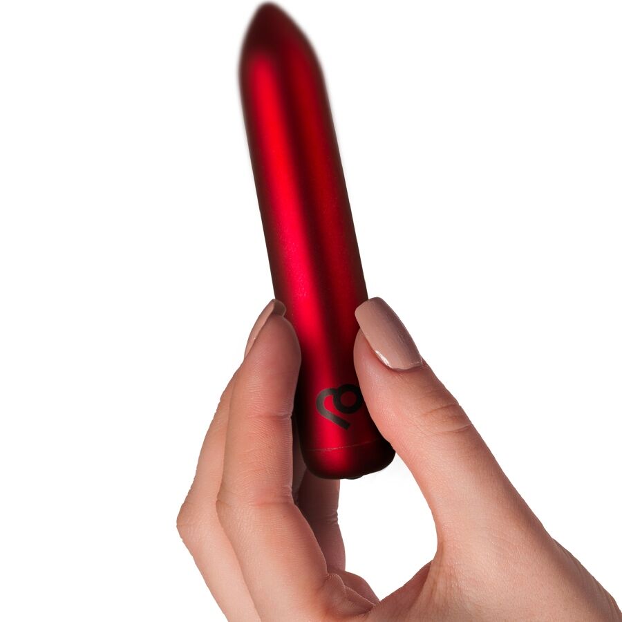 Bullet vibrant rouge tenu entre les doigts d'une main, montrant le format compact et discret de ce mini vibromasseur clitoridien rechargeable 16 fonctions Rocks-Off.