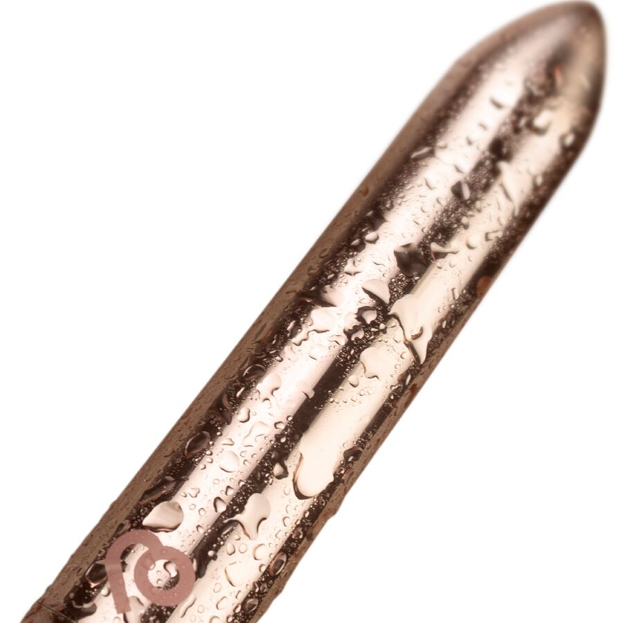 Gros plan du bullet vibrant doré couvert de gouttes d'eau, surface métallisée perlée mettant en avant l'étanchéité de ce mini vibromasseur clitoridien rechargeable.