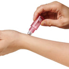Application du parfum roll-on aux phéromones Sunny Daze sur le poignet, bille rose qui depose la fragrance frais et floral du coffret duo femme Eye Of Love.