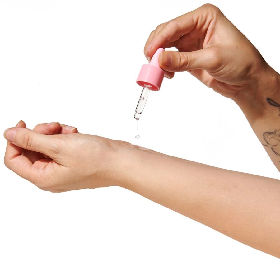 Application de l'huile de parfum aux phéromones Lilac Dream a la pipette sur le poignet, goutte deposee sur la peau, fragrance vanille musc Pheromone Perfume Oil Eye Of Love.