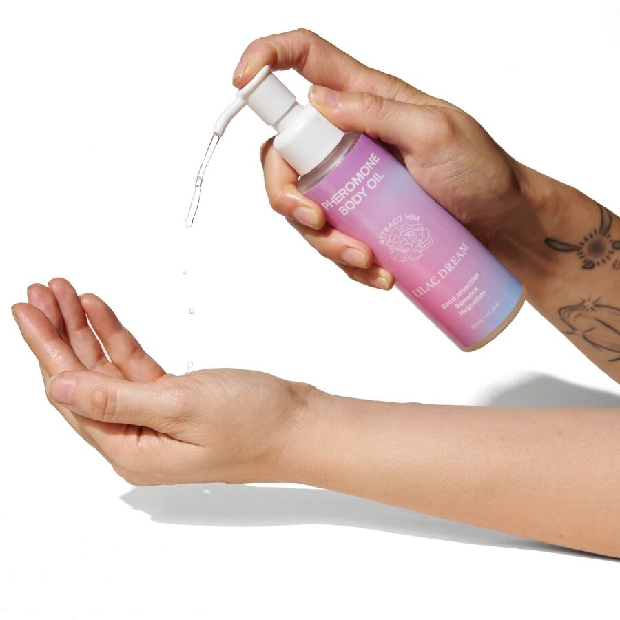 Huile corporelle aux phéromones Lilac Dream pompee dans le creux de la main, flacon degrade Pheromone Body Oil deposant un voile d'huile parfumee vanille musc sur la peau.